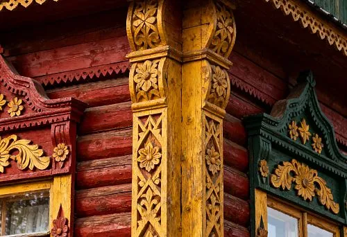 Carved wooden facade decoration with floral ornaments on walls and windows of a traditional house