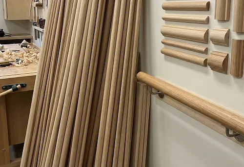 Round wooden handrail on brackets in the workshop, smooth sanded surface and precise diameter