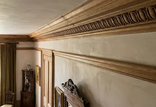 Wooden cornice under the ceiling with classic ornament, warm shade, and expressive relief