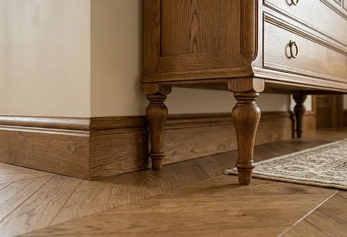 Wooden baseboard and furniture legs in matching tone: uniform height and style for dresser and walls