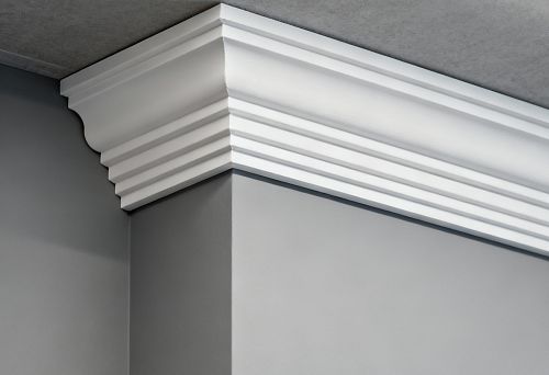 White ceiling profile installed on an internal wall corner, demonstrating the shape and relief of polystyrene or polyurethane skirting board