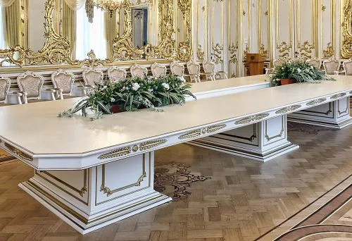 Luxurious white table base with gold ornamentation in a classical palace hall interior