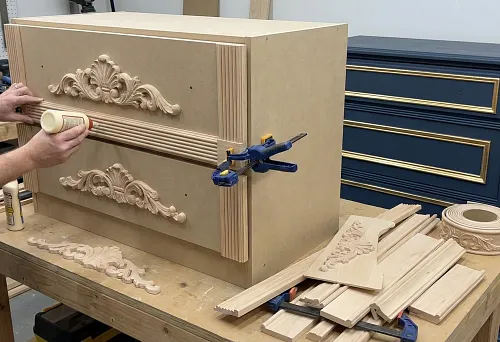 Solid wood furniture overlays: a craftsman glues carved decor onto a dresser facade in the workshop