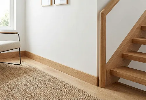 Wooden floor skirting and round staircase handrail: uniform wood tone, light wall, neat floor junctions.