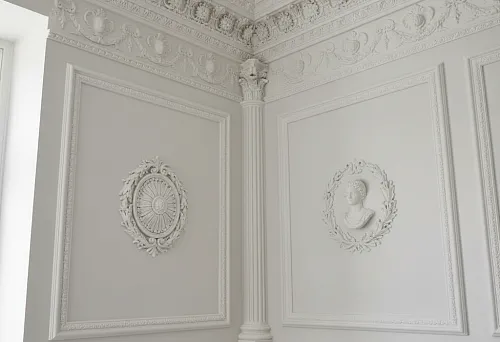 Interior with detailed molding on walls and ceiling, including profiles, ornaments, and columns