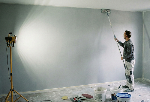 a craftsman prepares a wall for painting by leveling the surface
