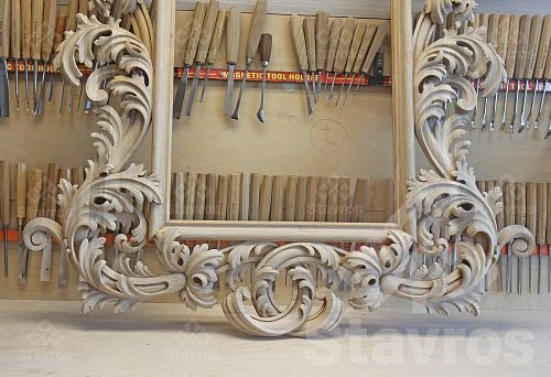 Luxurious hand-carved wooden frame in the workshop, against a backdrop of professional chisels and gouges