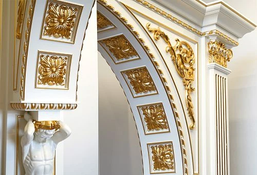 Luxurious interior with a decorative arch adorned with carved wooden elements and gold leaf.