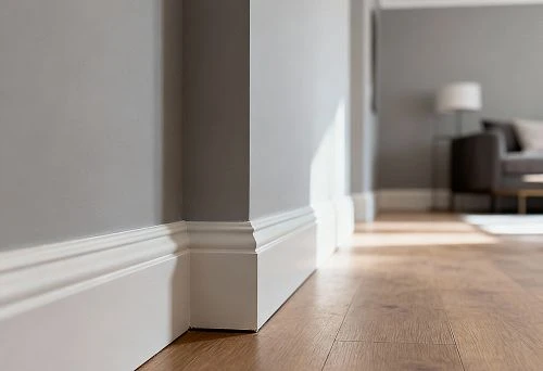 White baseboards against gray walls and wooden flooring.