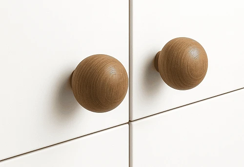 Two round wooden furniture handles on a white cabinet facade,