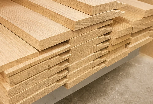 A stack of neatly cut light oak wooden skirting boards, prepared for installation in interior