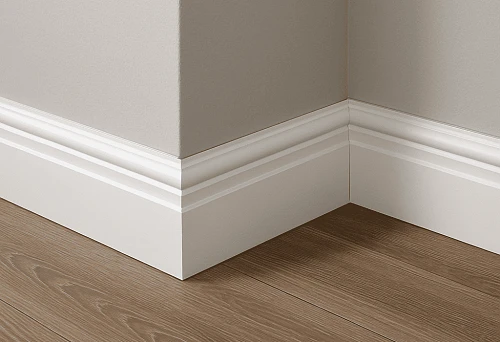 White medium-thickness skirting board at the junction of gray wall and wooden floor