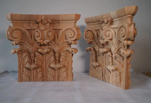 A pair of carved Corinthian-style oak capitals &mdash; intricate acanthus relief