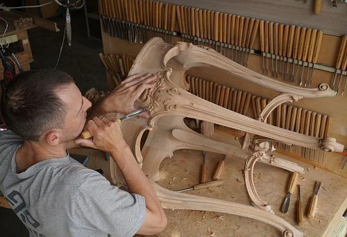 The master hand-carves an exquisite pattern on an unpainted wooden table