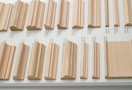 Samples of decorative wooden planks in various shapes and sizes on display, marked with profiles and cross-sections