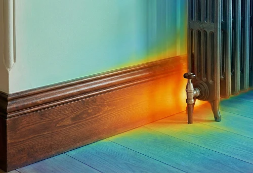Wide wooden baseboard near the wall and radiator: thermal map shows heat loss zones at the floor