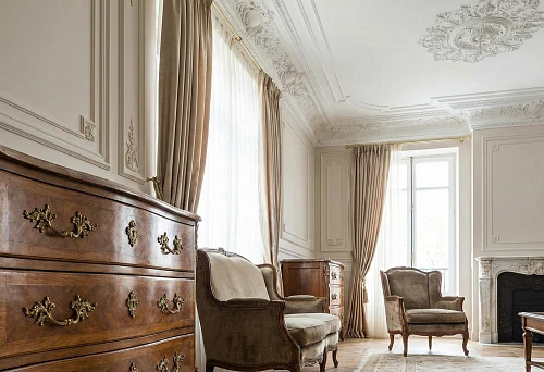 Furniture handles and polyurethane moldings in a classic interior: a chest of drawers with decorative hardware and molded decor on the ceiling