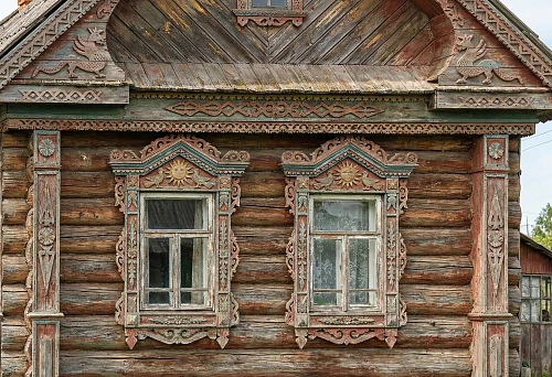 Decorating wooden facades with carving: house carving, carved architraves and cornice on an old wooden house
