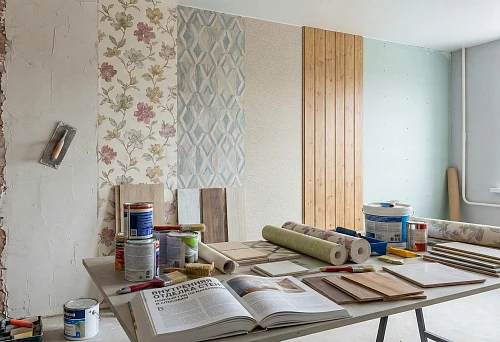 Work area with materials for interior wall finishing: wallpaper, paint, panels, and tools.