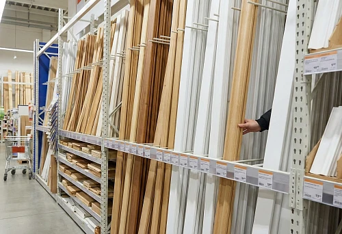 Shelf with moldings and trims for painting at a hardware store: selection of profiles for interior doors individually.