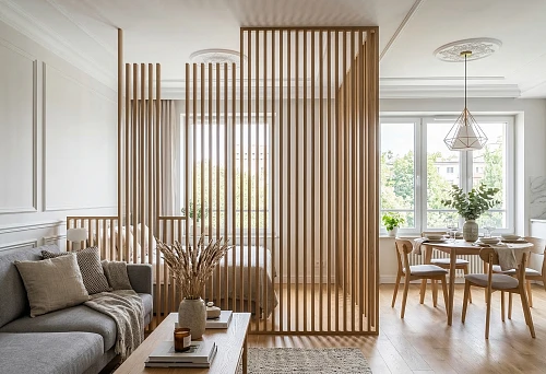 Slat panels for partitions and decorative polyurethane elements in a light studio interior with a lounge area and a dining table