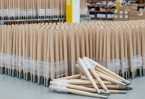 Set of identical wooden chair legs for serial production, arranged in a row demonstrating precise geometry and surface finish quality