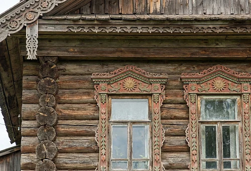 Wooden window decorations on the facade: carved architraves with ornament and a window-top element with a sun symbol