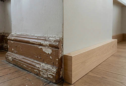 Old Soviet-style wooden baseboard with peeling paint on the wall and parquet floor
