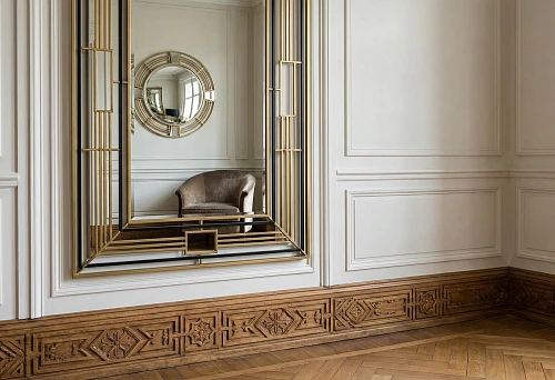 Mirror in art deco frame against classic wall panels made of moldings and high wooden baseboard with geometric carving