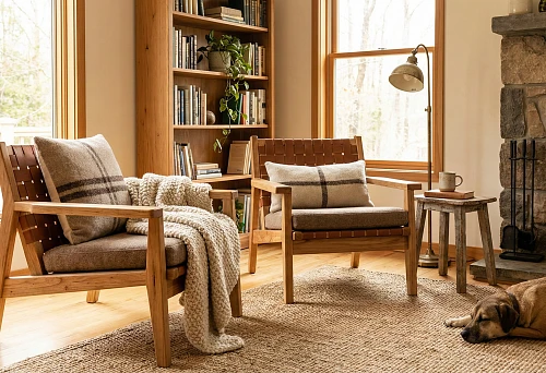 Reading nook: two solid wood armchairs by the window, a blanket and pillows in a cozy living room