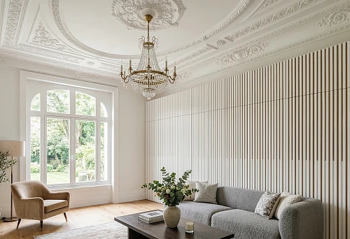 White slatted wall panel and ceiling molding in a bright living room interior with a chandelier and soft furniture