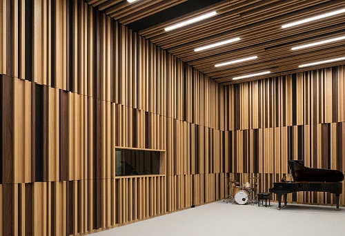 Acoustic studio with wooden linear panels of varying thickness on walls and ceiling, piano and drum set in the background
