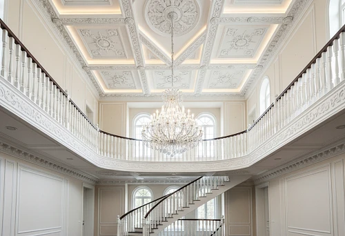Double-height hall with decorative ceiling molding that connects two floors into a single architectural composition