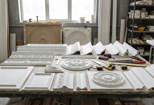 Cost of polyurethane stucco: samples of cornices, moldings, and rosettes on a workbench in the workshop