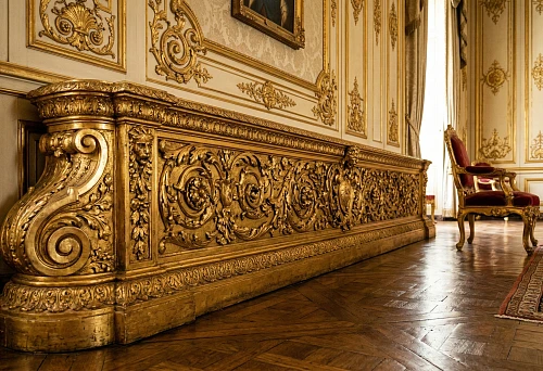 A tall gilded carved wooden baroque-style baseboard along the wall in the grand hall