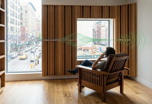 Living room with wooden acoustic panels and a large window facing the street: wood reduces the perception of urban noise