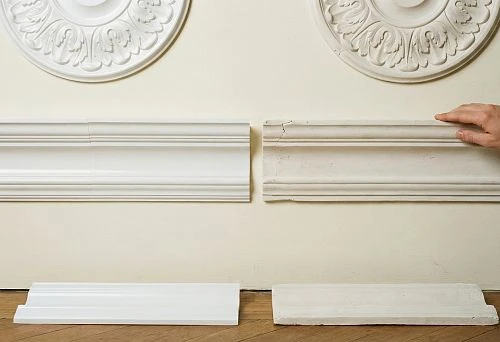 Comparison of two types of molding elements: new polyurethane moldings on the left and worn plaster elements on the right