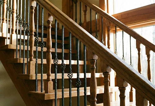 Staircase with wooden and metal balusters in warm interior of country house