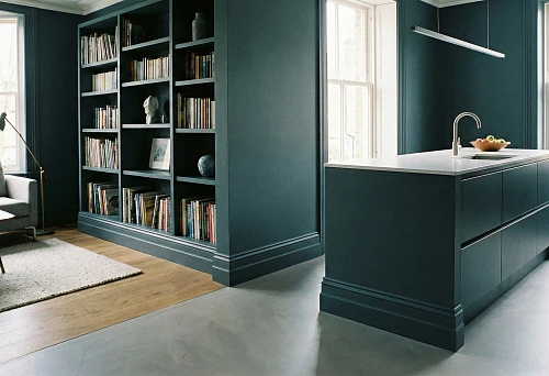 MDF skirting board in a dark interior &mdash; a kitchen-living room with deep blue-green walls and facades, the dark skirting board emphasizes the geometry and visually "assembles" the space