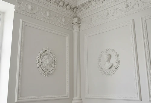 Interior with detailed molding on walls and ceiling, including profiles, ornaments, and columns