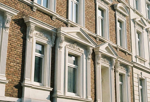 Facade windows with polyurethane decorative frames on a brick house