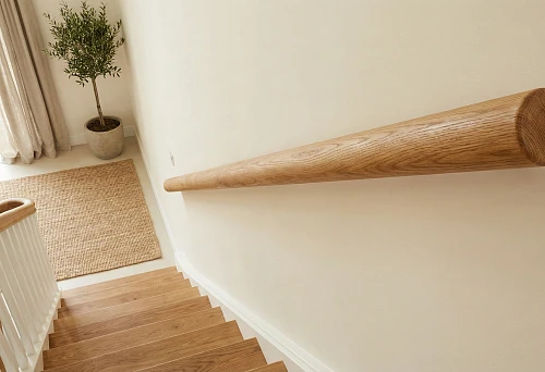 Round wooden handrail on the staircase wall: natural wood texture, smooth sanding, light interior.