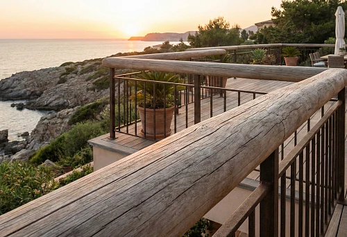 Outdoor terrace railing: round wooden handrail and metal balusters, panoramic view of the coast
