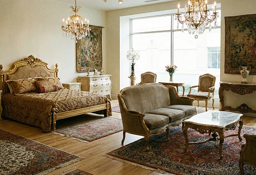 Bedroom interior in classical style with carved bed, upholstered furniture, and crystal chandeliers