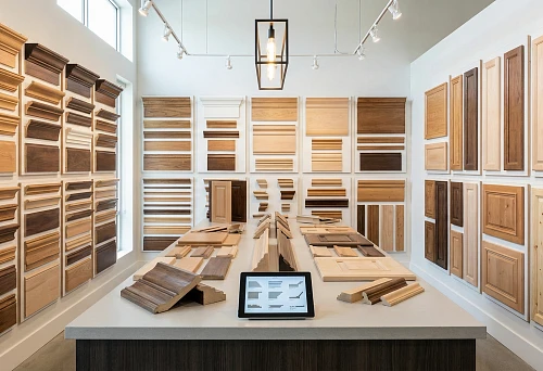Wooden Molding Products: A showroom with stands of profiles, moldings, and panels in various shades, samples laid out on a table.