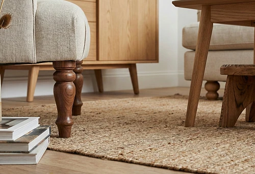 Solid wood furniture legs: turned wooden sofa supports against a natural fiber carpet