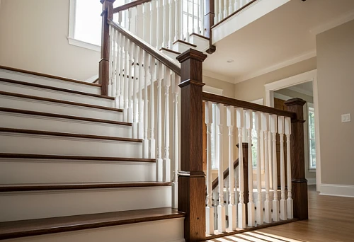 Staircase with oak handrails and white solid wood balusters in a classic interior with warm lighting