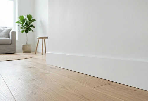 White narrow wooden skirting board without profile in Scandinavian interior on light wooden floor