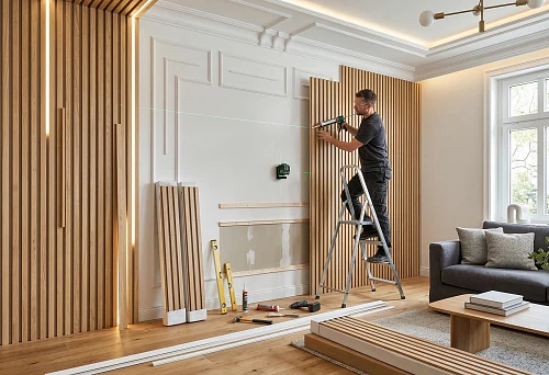 Ready-made slatted wall panels and interior moldings during installation in a modern bright living room