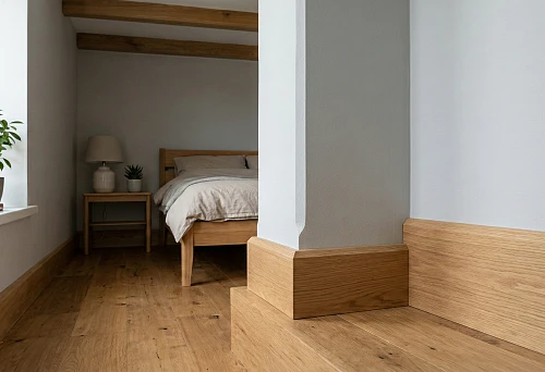 Low-profile wooden skirting board in a small bedroom: neat line against light wall and wooden floor
